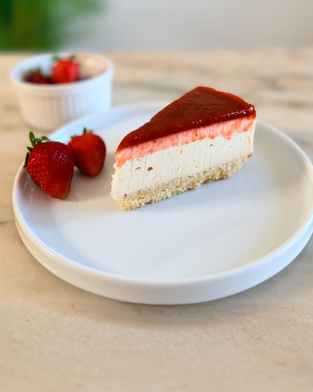A slice of strawberry cheesecake on a white plate